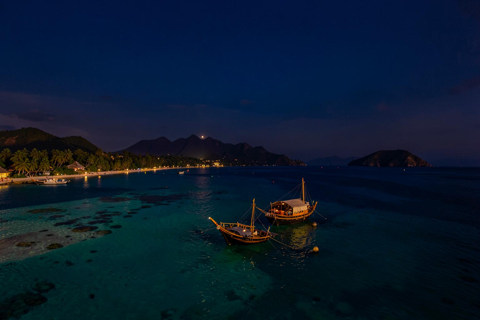 Dhows anchored on turquoise water off the Zanzibar coast at dusk